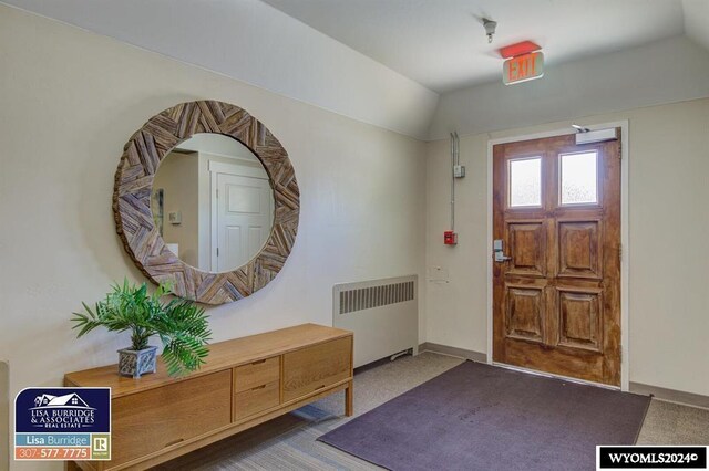 foyer featuring lofted ceiling, radiator, and carpet floors