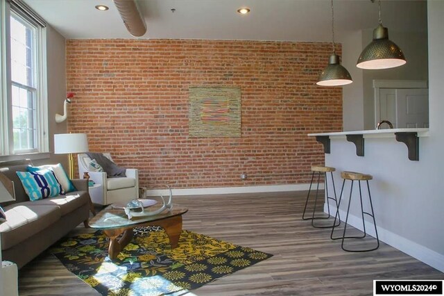 living room with dark hardwood / wood-style floors, plenty of natural light, and brick wall