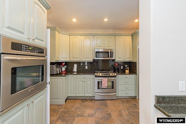 kitchen with dark tile floors, backsplash, and stainless steel appliances