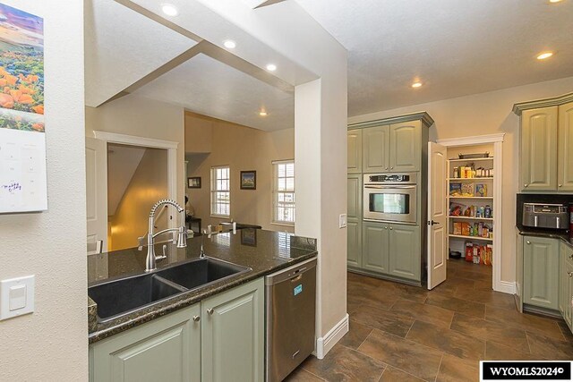 kitchen with sink, dark tile flooring, stainless steel appliances, and dark stone counters