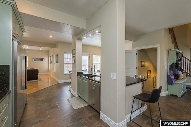 kitchen with dark tile floors, appliances with stainless steel finishes, a kitchen bar, and sink