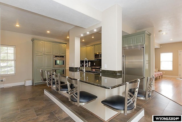 kitchen featuring kitchen peninsula, stainless steel appliances, dark wood-type flooring, a kitchen breakfast bar, and sink