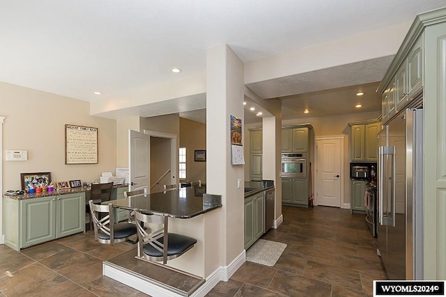 kitchen with dark tile flooring, stainless steel appliances, kitchen peninsula, and a breakfast bar