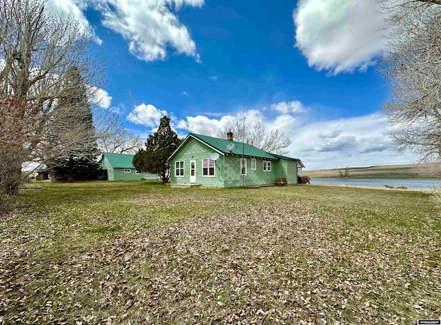 view of home's exterior with a water view and a lawn