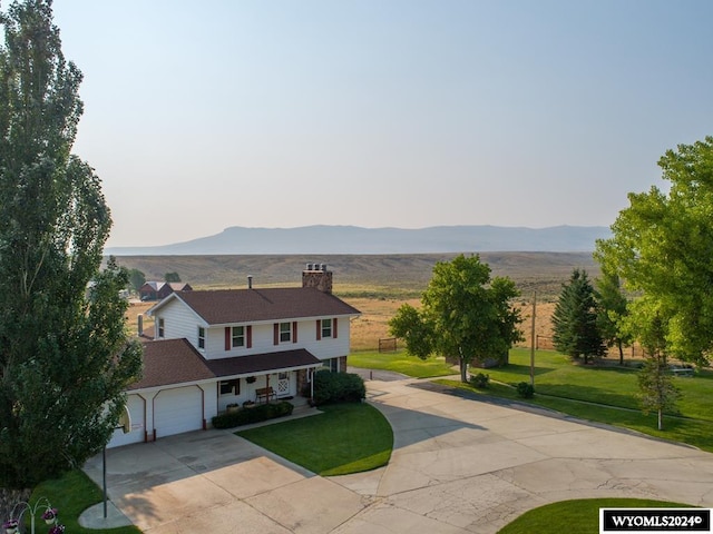 view of front facade with a front yard, a garage, and a mountain view