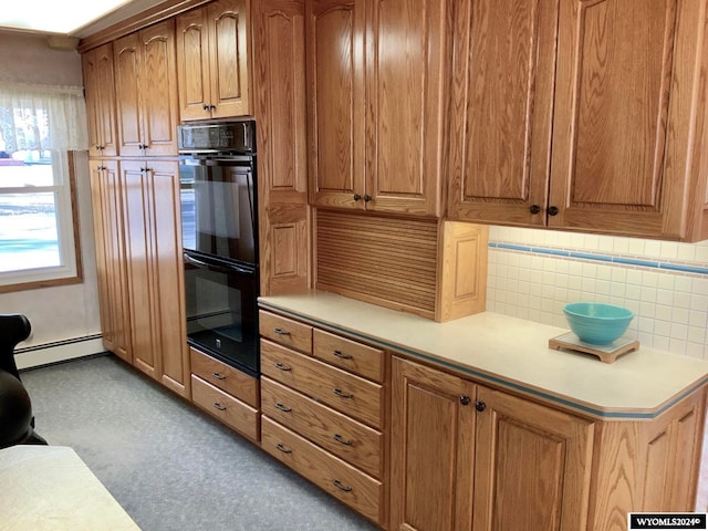 kitchen featuring baseboard heating, tasteful backsplash, and black double oven