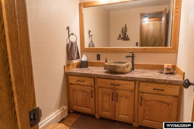 bathroom featuring hardwood / wood-style floors, baseboard heating, and vanity