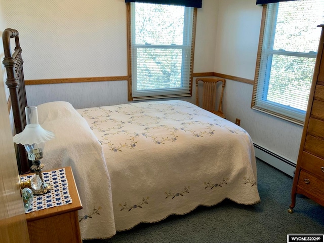 bedroom featuring a baseboard heating unit and dark colored carpet