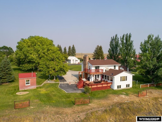 rear view of house with a wooden deck, a lawn, and a patio