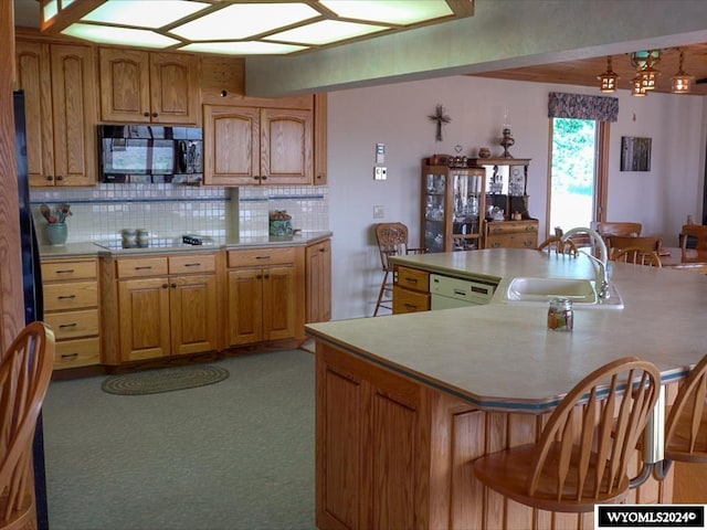 kitchen with black appliances, light colored carpet, backsplash, sink, and a kitchen bar