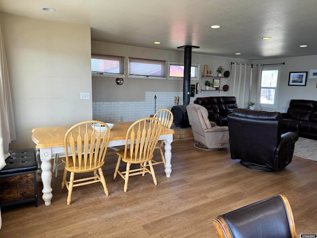 dining space featuring wood-type flooring and a wood stove