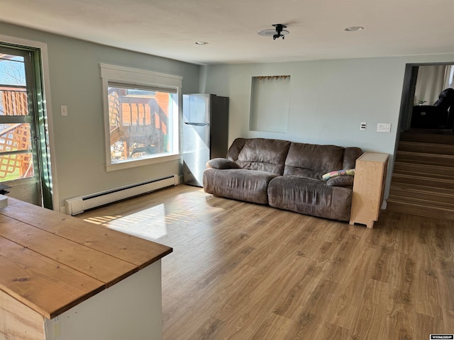 living room with baseboard heating and wood-type flooring