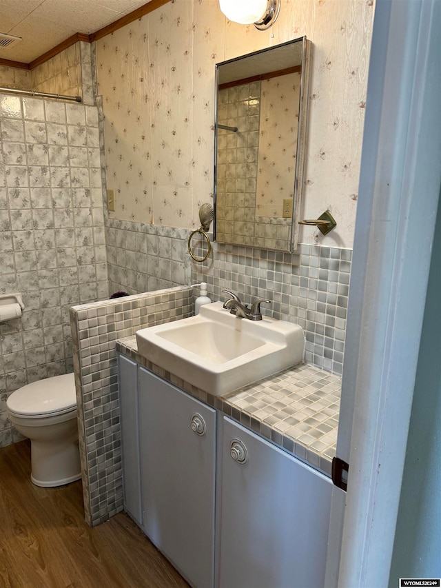 bathroom with tile walls, hardwood / wood-style flooring, vanity, and toilet