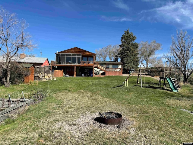 view of yard with a deck, a playground, and an outdoor fire pit