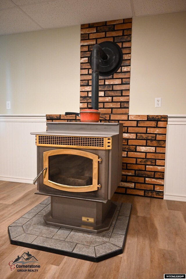 room details with hardwood / wood-style floors, a wood stove, and a drop ceiling