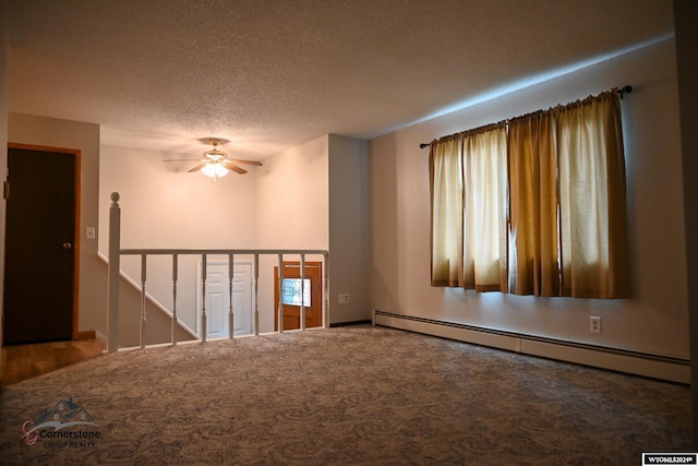 carpeted spare room with ceiling fan, a wealth of natural light, a textured ceiling, and a baseboard heating unit