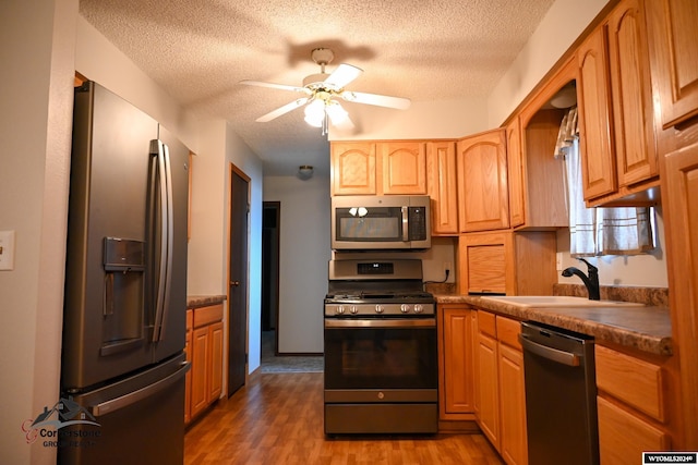 kitchen featuring dark hardwood / wood-style floors, sink, ceiling fan, stainless steel appliances, and a textured ceiling