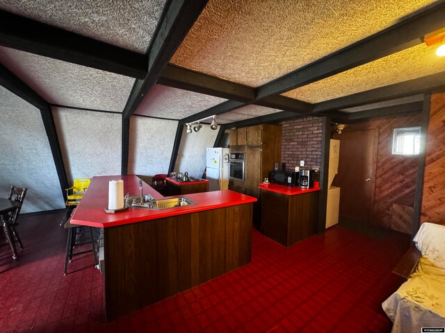 interior space with a textured ceiling, brick wall, dark colored carpet, oven, and white fridge