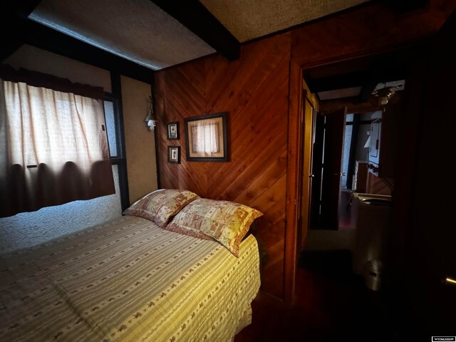 carpeted bedroom with beamed ceiling and wooden walls