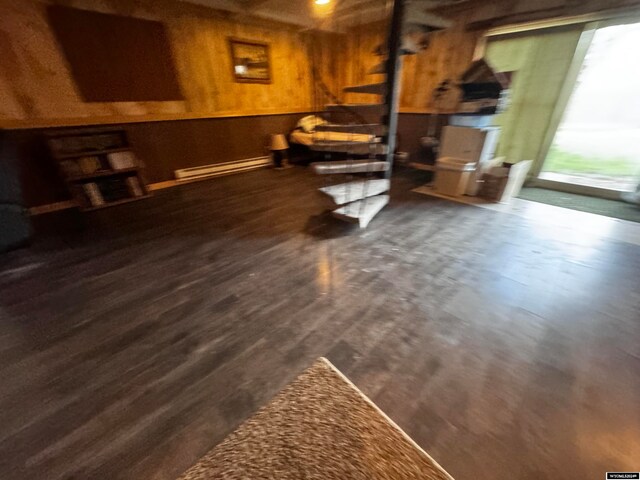 basement featuring a baseboard radiator, dark hardwood / wood-style floors, and wooden walls