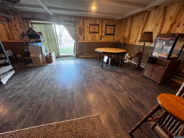 dining area featuring a baseboard heating unit, dark hardwood / wood-style flooring, and wooden walls