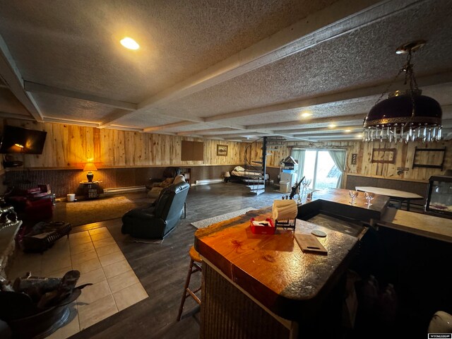 dining space with a baseboard heating unit, beam ceiling, a textured ceiling, and wood-type flooring