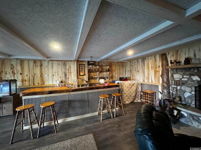 bar with beamed ceiling, a textured ceiling, and wood walls