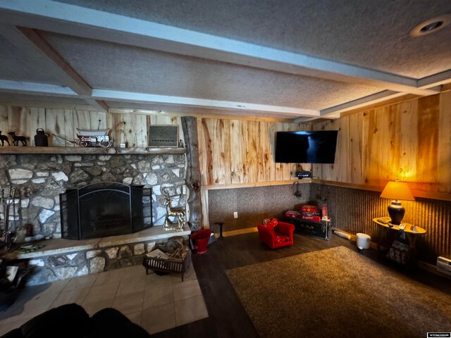 unfurnished living room featuring a stone fireplace, beam ceiling, and a textured ceiling