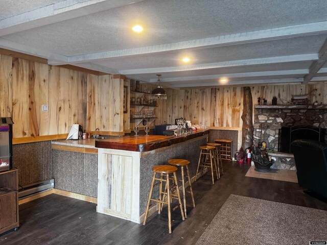 interior space featuring dark hardwood / wood-style floors, kitchen peninsula, a fireplace, a baseboard radiator, and a kitchen bar