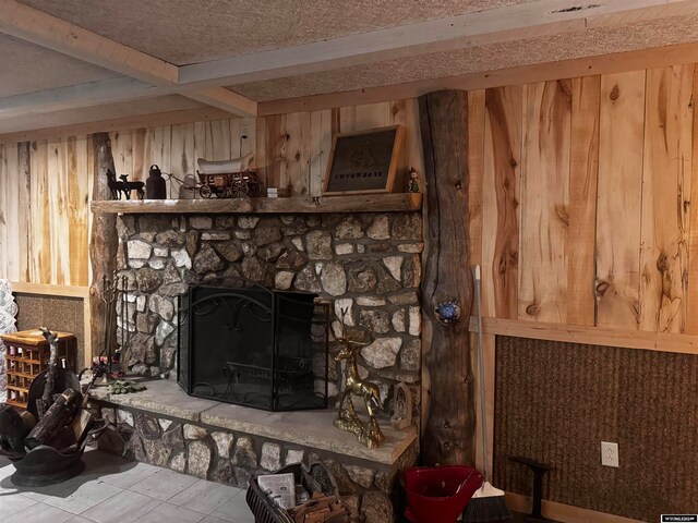 room details featuring a stone fireplace, tile flooring, and beamed ceiling