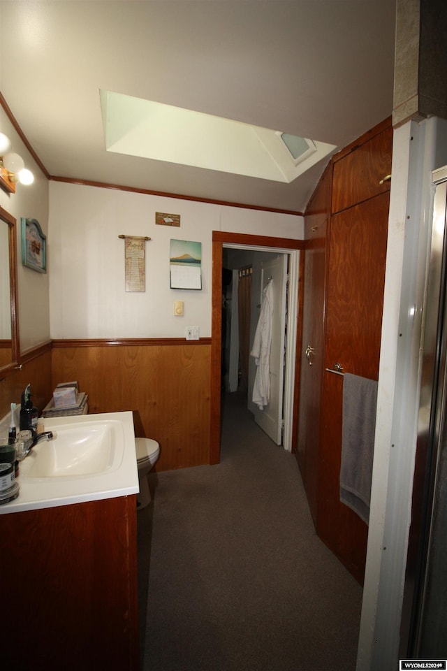 bathroom featuring vanity, toilet, ornamental molding, and wooden walls