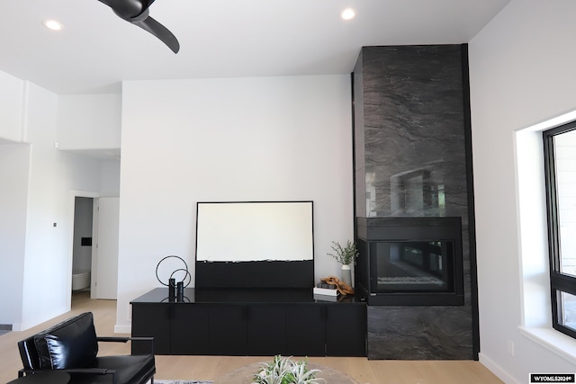 living room featuring a wealth of natural light, ceiling fan, a large fireplace, and hardwood / wood-style flooring