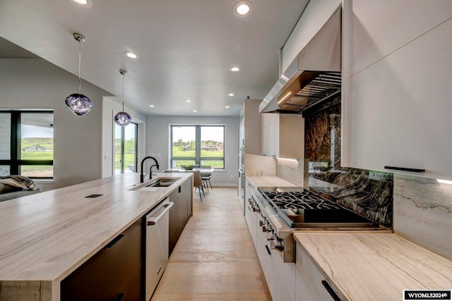 kitchen featuring white cabinets, stainless steel appliances, tasteful backsplash, sink, and pendant lighting