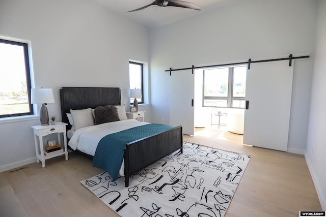 bedroom with a barn door, multiple windows, and light hardwood / wood-style flooring