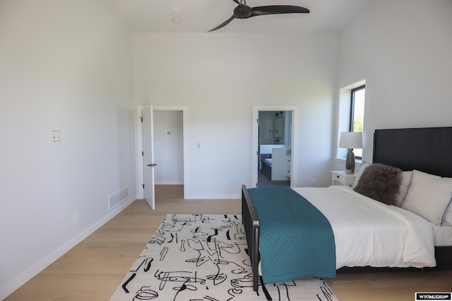 bedroom with hardwood / wood-style floors, ensuite bathroom, a high ceiling, and ceiling fan