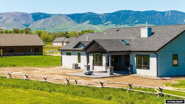 back of property with a patio, a mountain view, and a yard