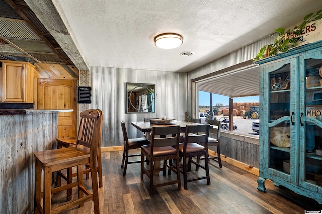 dining room featuring a textured ceiling, dark hardwood / wood-style flooring, and wood walls