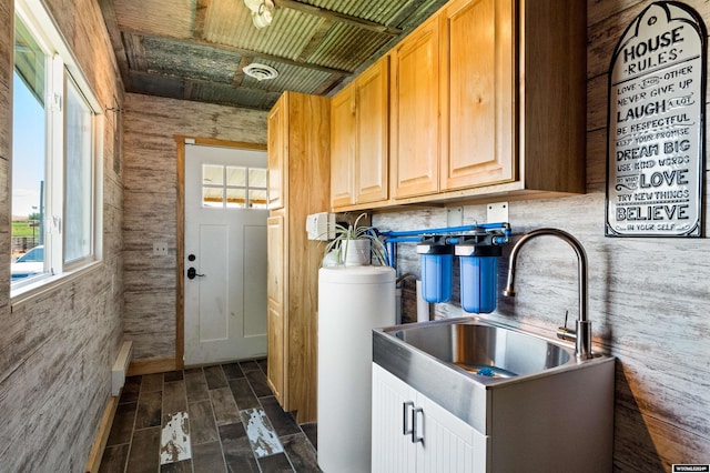 interior space with dark hardwood / wood-style flooring, wooden walls, sink, and cabinets