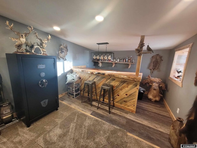 bar with dark hardwood / wood-style flooring, decorative light fixtures, and vaulted ceiling