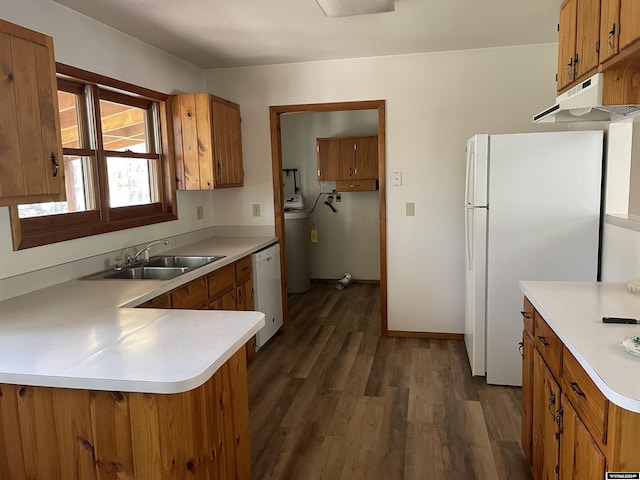 kitchen featuring white appliances, sink, water heater, dark hardwood / wood-style flooring, and kitchen peninsula