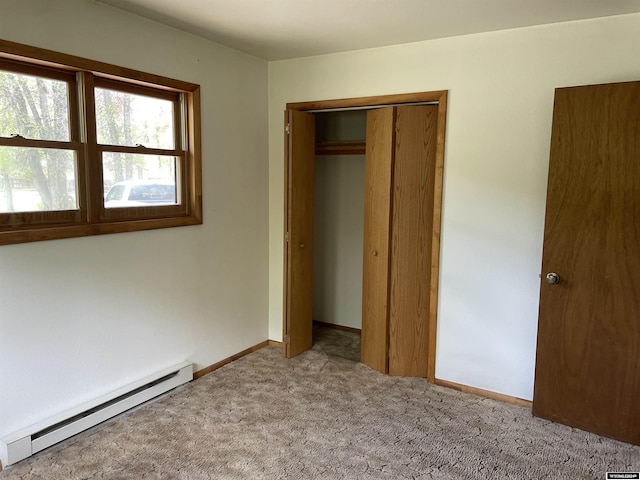 unfurnished bedroom featuring light carpet, a closet, and baseboard heating