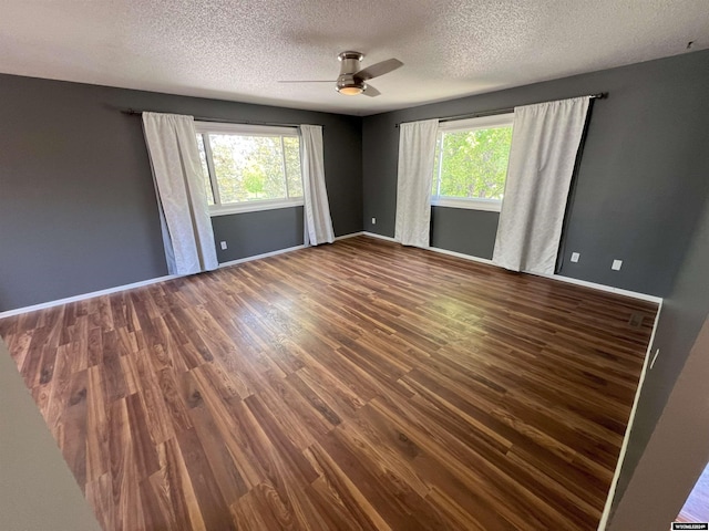 spare room featuring a healthy amount of sunlight, dark hardwood / wood-style flooring, and a textured ceiling