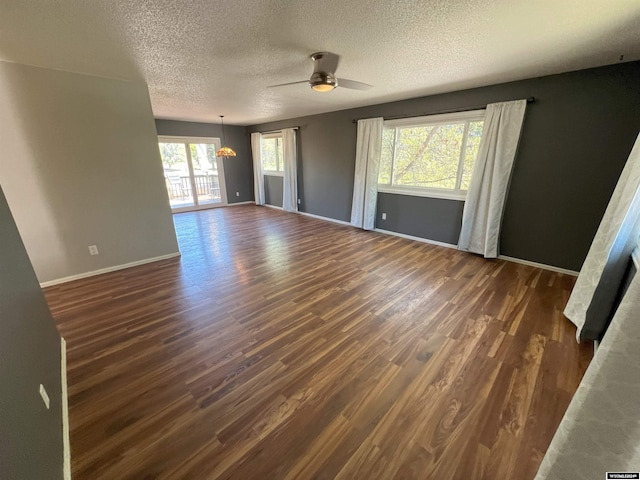 unfurnished living room with a textured ceiling, dark hardwood / wood-style flooring, plenty of natural light, and ceiling fan