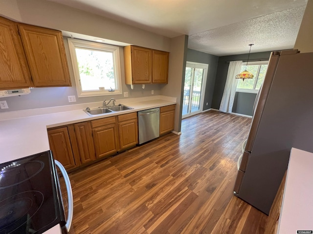 kitchen with appliances with stainless steel finishes, a wealth of natural light, hanging light fixtures, and sink