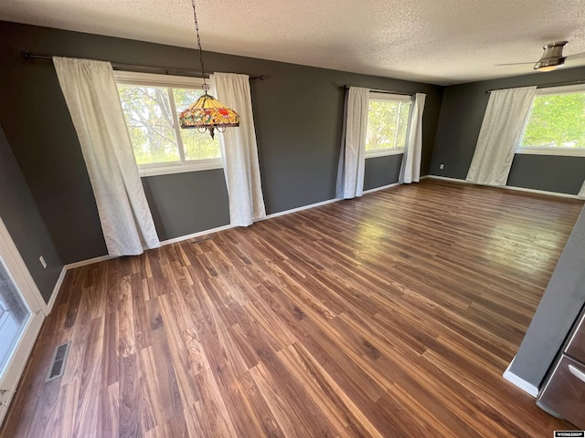 unfurnished dining area featuring ceiling fan, dark hardwood / wood-style flooring, and a textured ceiling