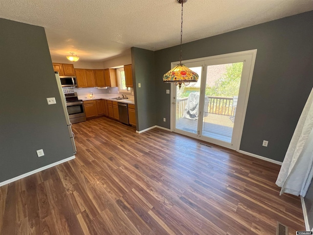 4012 Prestwick Pl, Riverton, WY 82501 - kitchen with appliances with stainless steel finishes, light countertops, dark wood-style floors, a textured ceiling, and decorative light fixtures