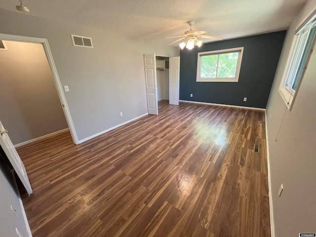 unfurnished bedroom featuring a textured ceiling, dark hardwood / wood-style floors, and ceiling fan