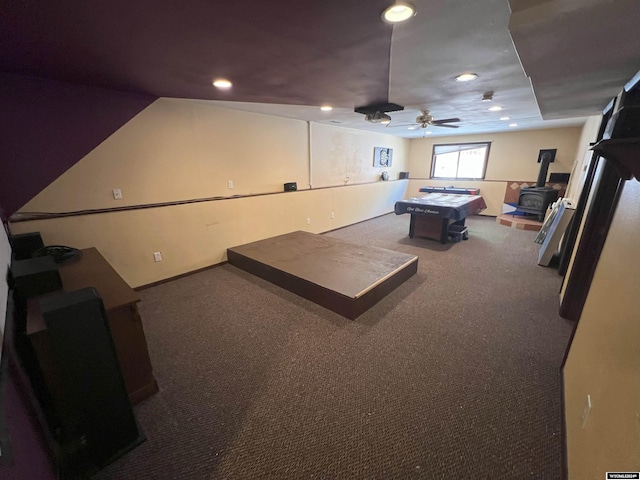 playroom featuring carpet flooring, ceiling fan, and a wood stove