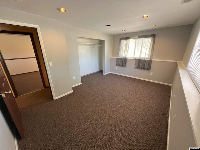 unfurnished bedroom with dark colored carpet and a closet