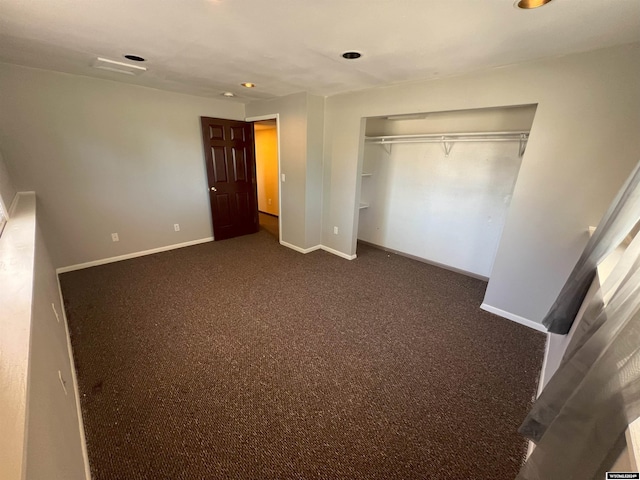 unfurnished bedroom with dark colored carpet and a closet